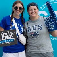 two students posing in front of CAB backdrop at Laker Kickoff photo booth and smiling with a GV sign and foam finger
